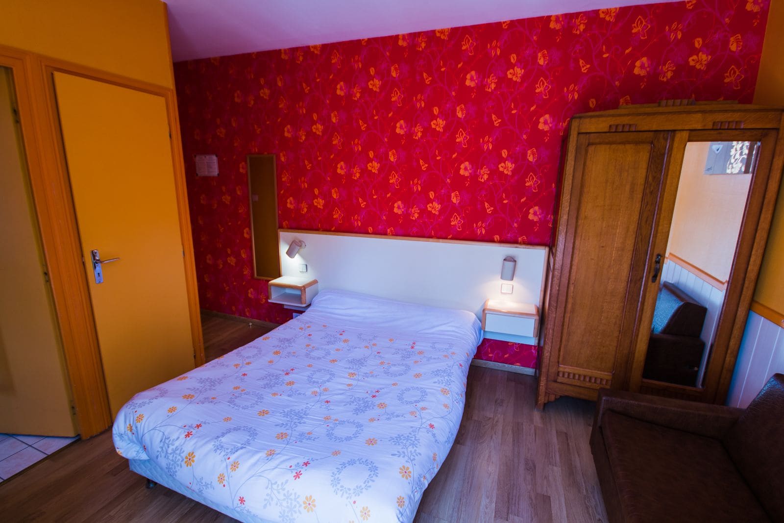 Une chambre à coucher avec un lit, des tables de chevet, une armoire et une porte.