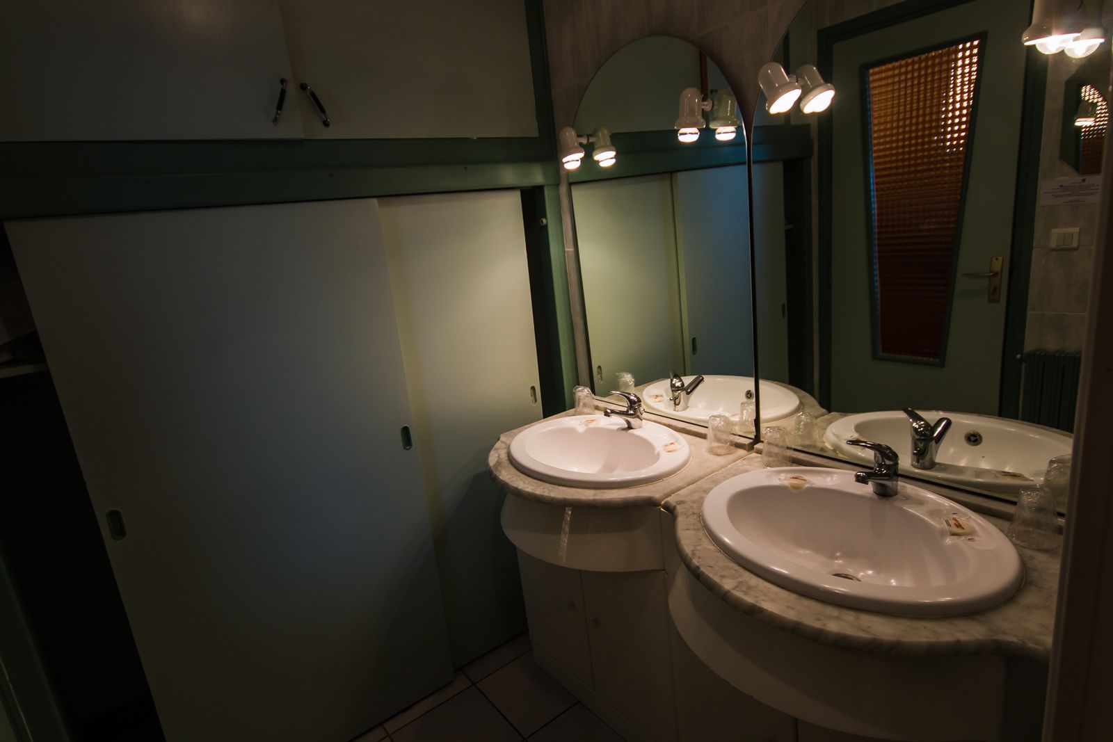 Un baño con dos lavamanos, un espejo e iluminación en el techo.