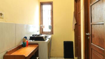 A narrow hallway with a wooden bench, a washing machine, and a small window.