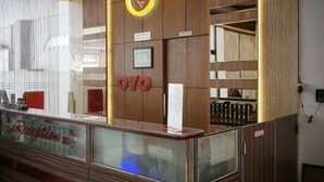 A reception desk with a glass partition, wooden paneling, and a sign reading "Reception".