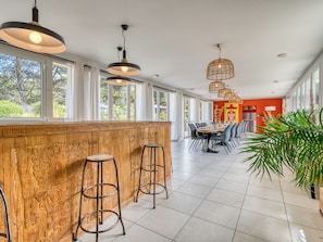 Un restaurante con barra de madera, sillas altas y lámparas colgantes.