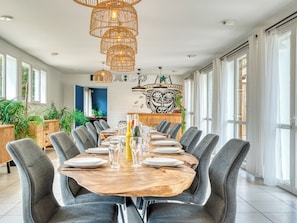 A dining area with a long wooden table set for a meal, surrounded by grey upholstered chairs.