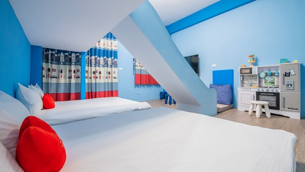 Une chambre d’hôtel moderne avec deux lits, un espace de jeux et une kitchenette.