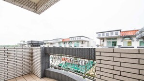Une terrasse sur le toit offrant une vue sur les bâtiments voisins et dotée d’une rambarde en métal.