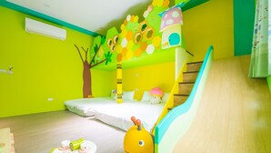 Une chambre d’enfant aux couleurs vives, avec un lit superposé, une petite table avec des jouets et un toboggan.