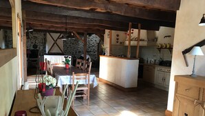 Eine rustikale Küche mit Steinwand, Holzbalken und Fliesenboden.