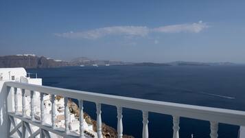 A coastal view with white buildings, a balcony railing, and the sea.