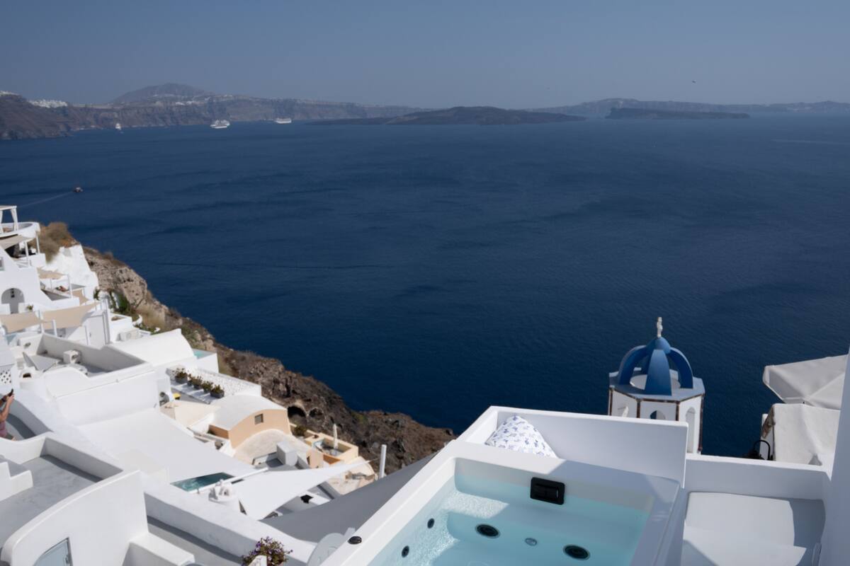 Blick auf die Küste mit weißen Gebäuden, einer blauen Kuppel und klarem Meer.