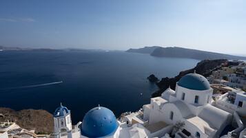 A coastal town with white buildings and blue domes, overlooking the sea.
