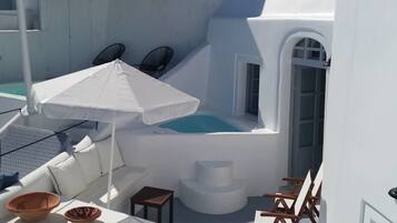 Un espacio exterior moderno y luminoso con jacuzzi, sillones de descanso y sombrillas.