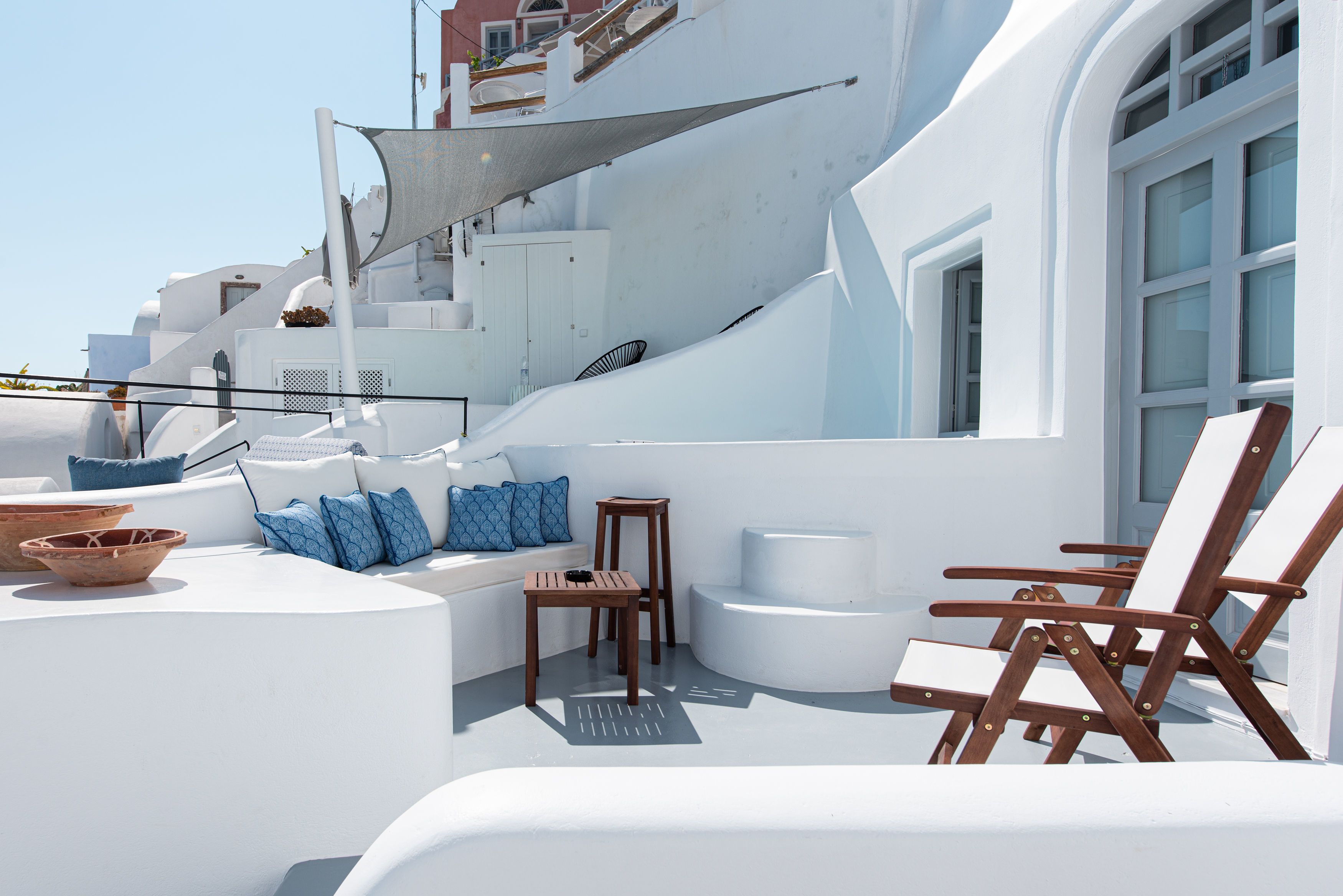 Una terraza blanca y curva con una zona de estar, que incluye una mesa y sillas, y un ventanal grande.