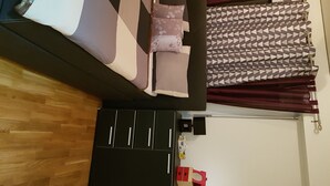 Une chambre à coucher avec un lit, une commode, un miroir et une fenêtre avec des rideaux.