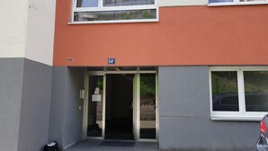 Une entrée d’immeuble avec une porte, un numéro bien visible, le « 84 », et une voiture garée.