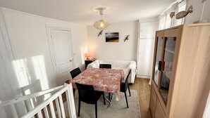 A compact room with a dining table, chairs, a small lamp, and a cabinet.