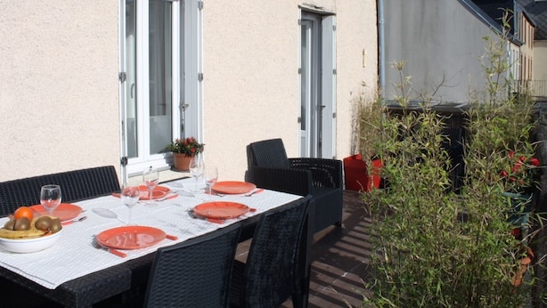 An outdoor dining area with a table set for four, surrounded by wicker chairs.
