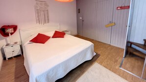 A bedroom with a bed, a nightstand, a lamp, a wall decoration, and a door.
