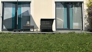 Una casa moderna con un amplio ventanal corredero, un ventanuilla pequeña y un paraguas azul.