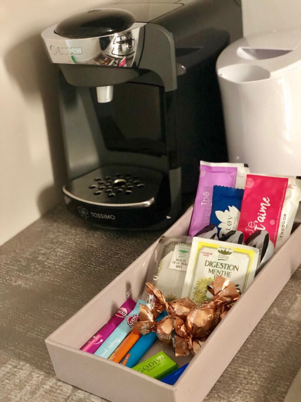 Una cafetera y una caja con variedad de productos de té y café.