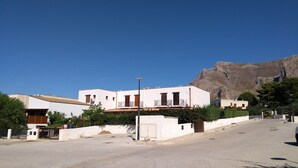 Una calle con edificios blancos, un farol y una montaña al fondo.