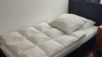 Un lit avec une tête de lit, un plancher en bois et un mur orné d’une œuvre d’art abstraite.