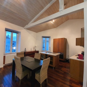 Una cocina compacta con armarios de madera, una mesa de comedor con sillas y vistas al exterior.