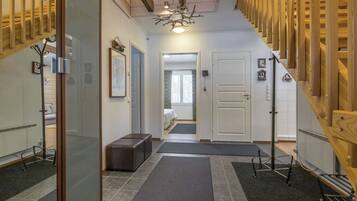 A hallway with a staircase, a bench, a door, and a mirror.