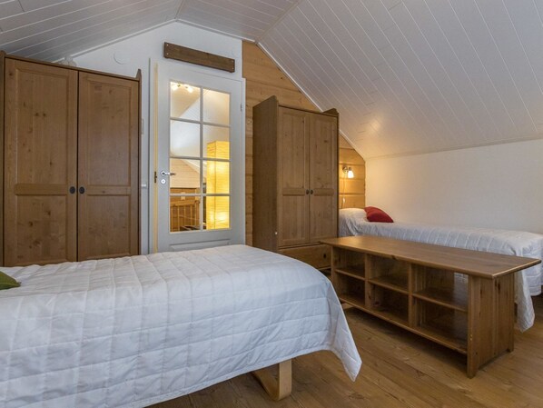 Une chambre mansardée chaleureuse, avec des meubles en bois, un lit en mezzanine et un petit bureau.