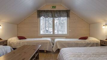 Una habitación con dos camas, una mesa de madera y un ventanal con vistas a árboles.