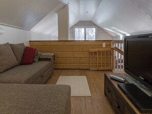 Una sala de estar acogedora con un sofá, un televisor y piso de madera.