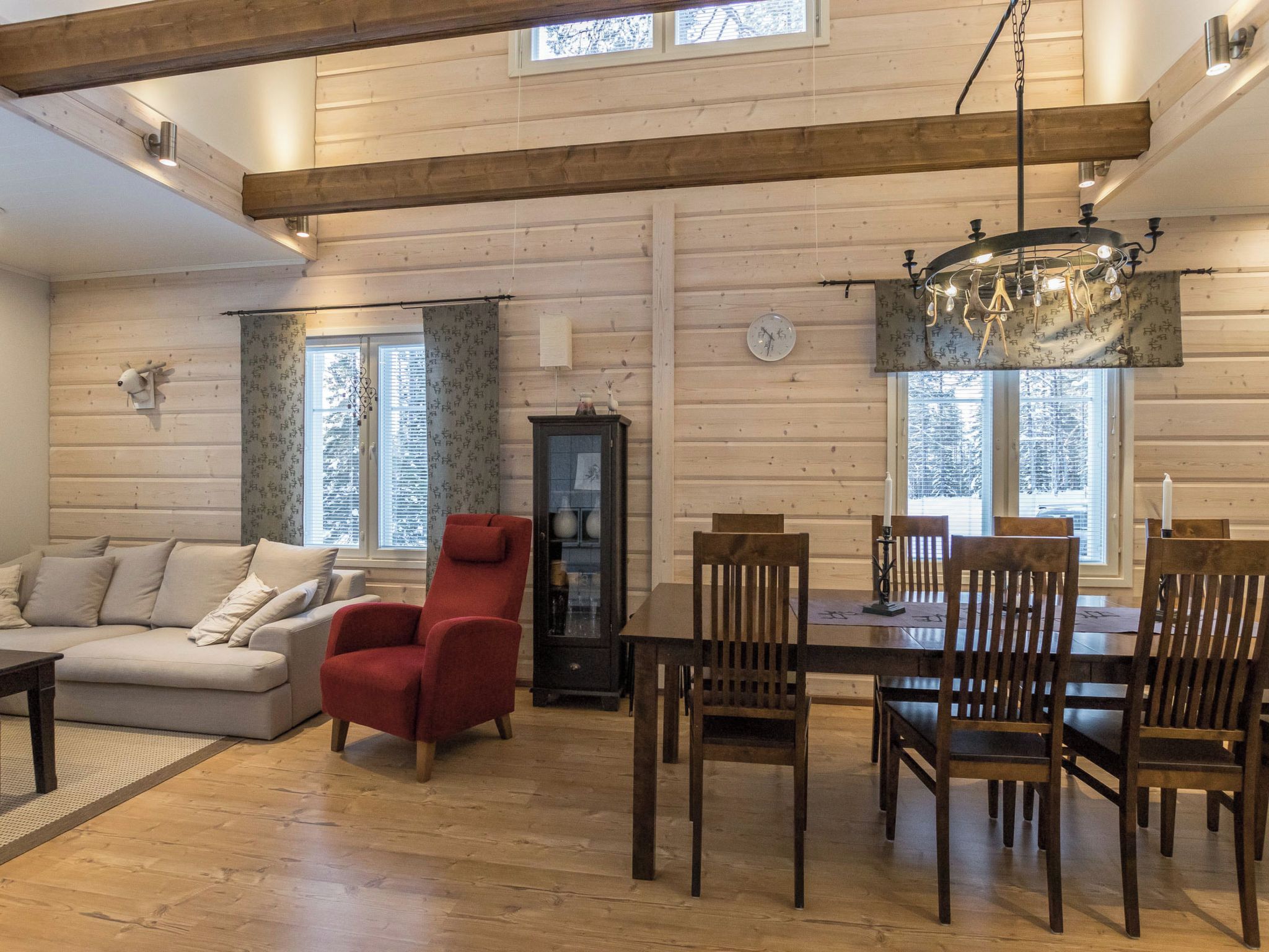 A spacious living room with a sofa, red armchair, and dining table with chairs.