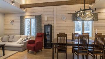 A spacious living room with a sofa, red armchair, and dining table with chairs.