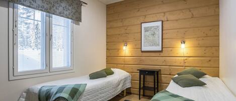 A room with two beds, a window with blinds, a wooden wall, and a framed picture.