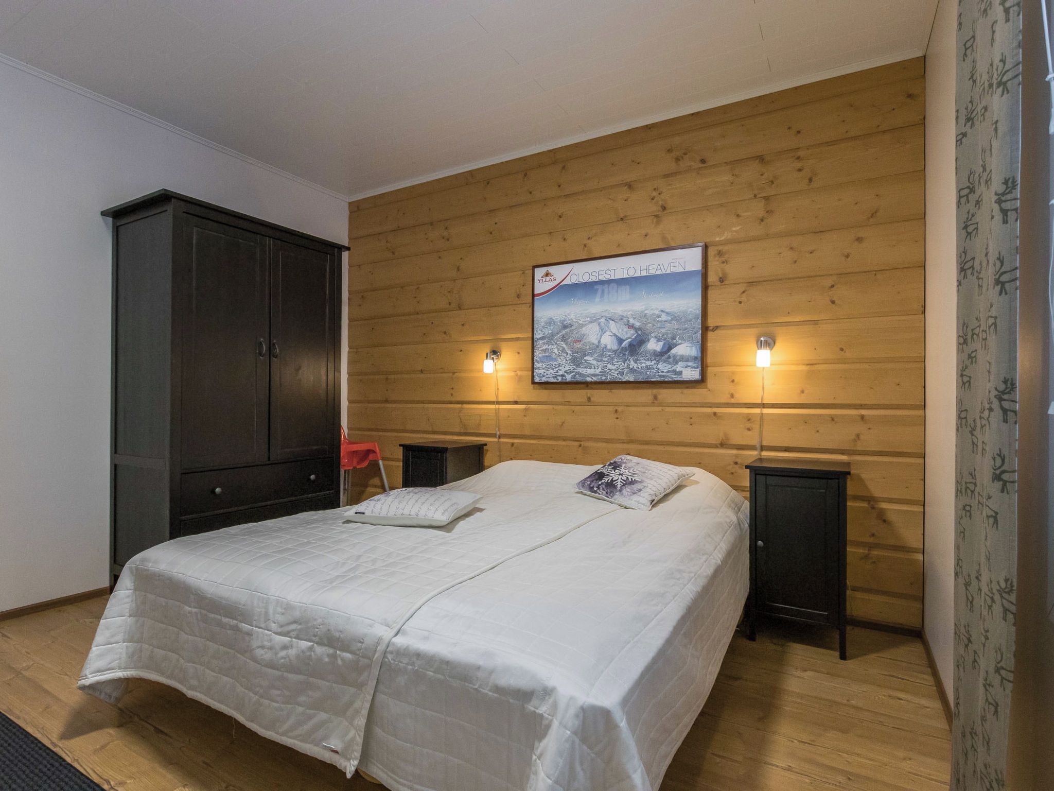 Une chambre à coucher avec une tête de lit en bois, un lit avec une literie blanche, deux tables de chevet et une petite table de nuit.