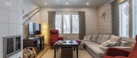 Una sala de estar moderna con chimenea, televisor, sofá y un sillón rojo.
