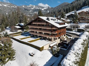 A multi-story hotel with a ski slope in the background.