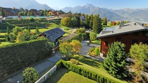 A residential area with houses, a swimming pool, and mountains in the background. - Sunset B 11 by Interhome (Villars)