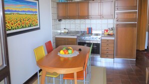Una cocina con armarios de madera, estufa y una mesa de comedor con sillas.