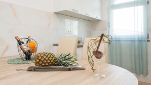 Une table à manger avec un ananas, une bouteille de vin et un verre de vin rouge.