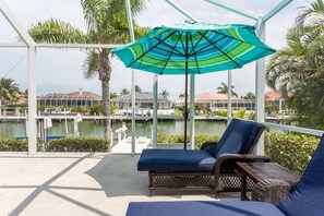 Relax in a serene outdoor space with a marina view, featuring a lounge chair and wicker table.