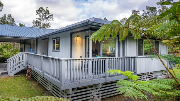 Ett modernt hus med en inglasad veranda, stora fönster och en trappa som leder upp till entrén.