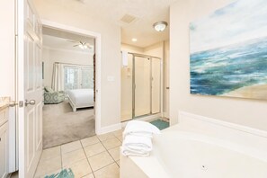 A bathroom with a bathtub, a shower, and a painting on the wall.