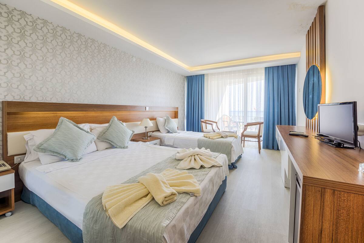 A hotel room with two beds, a desk, a television, and a bathroom.