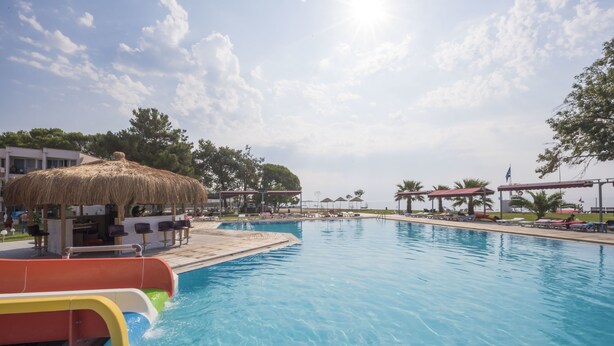 Una piscina con tobogán de agua, sillas de descanso y sombrillas.