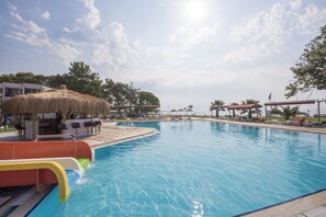 A swimming pool with a water slide, lounge chairs, and umbrellas. - RA RESORT OTEL (Edremit)