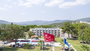 A hotel with a swimming pool, outdoor seating, and a view of mountains. - RA RESORT OTEL (Edremit)