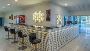 Un área de recepción moderna con mostrador, taburetes de bar y decoración mural hexagonal.
