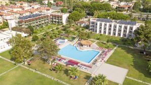 Vista aérea de un hotel con piscina, tumbonas y zona de juegos para niños.