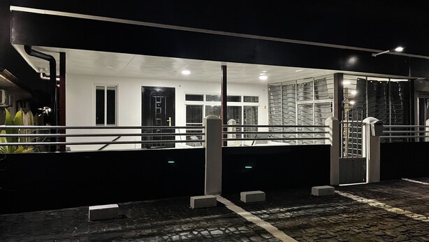 A modern building with a glass facade, a stone-paved entrance, and a metal railing. - D-Tas appartement en studio (Paramaribo)