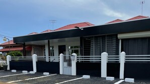 A modern building with a red roof, a gated entrance, and a paved driveway. - D-Tas appartement en studio (Paramaribo)