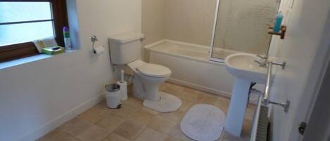 A bathroom with a toilet, bidet, bathtub, and sink.